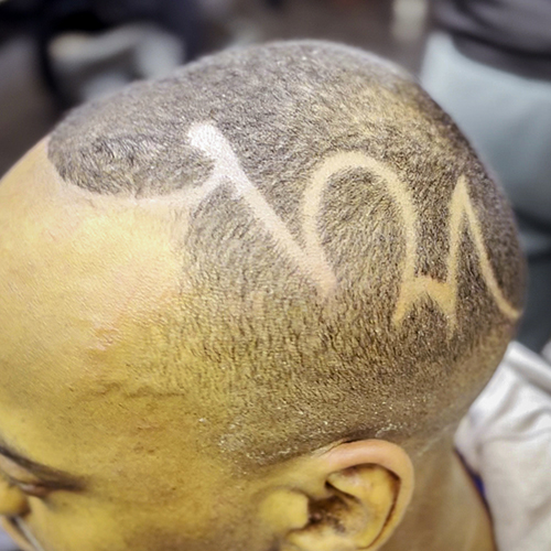 Freehand line-art design shaved into a client's fade